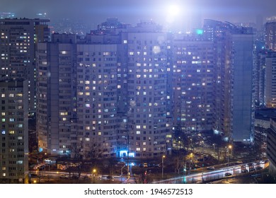 Residential Area Of Condominiums At Night. A Powerful Construction Crane Floodlight Illuminates High-rise Buildings And Creates Bright Reflections. Russia, Moscow - February 26, 2020