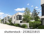 Residential area with ecological and sustainable green residential buildings, low-energy detached houses with white facade and flat roof, timber construction and green courtyard