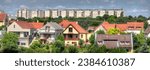 A residential area with single-family houses in a suburb of Veszprem, a city near Lake Balaton in Hungary, with a block of flats on a hill on the horizon