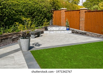 Residential back garden landscaped with light and dark grey porcelain paving slabs and artificial grass. No people. - Shutterstock ID 1971342767
