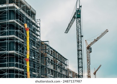 Residential building construction site with cranes and scaffolding equipment, low angle view - Powered by Shutterstock