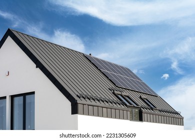 Residential building roof with solar photovoltaic panels on metal galvanized coating. Private house with renewable energy elements on rooftop. Advertising concepts