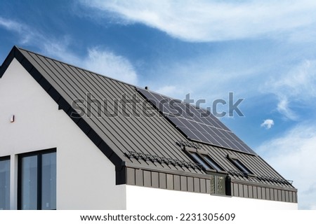 Residential building roof with solar photovoltaic panels on metal galvanized coating. Private house with renewable energy elements on rooftop. Advertising concepts