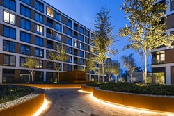 Residential Buildings In A European City At Night. Modern Blocks Of Flats. Courtyard With Vegetation And Lighting. Rust Metal Finish, Corten. Underground Garage