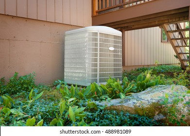 A Residential Central Air Conditioning And Heating Unit Sitting Outside A Home.