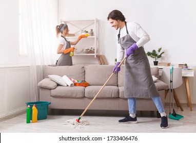 Residential Cleaning Services. Couple Of Skilled Housekeepers Man And Woman Tidying Up Apartment, Doing Household Together, Free Space