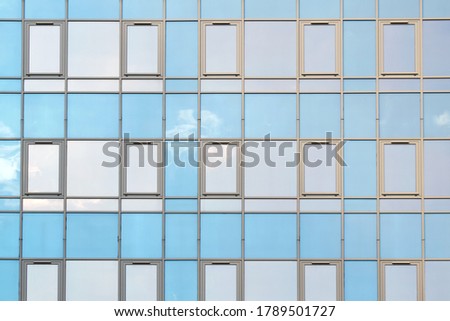 Residential complex with large mirrored windows on the facade with a reflection of the sky.
