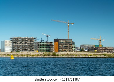 Residential construction on the Northern part of Amsterdam, the Netherlands. Modern waterfront apartment buildings, tower cranes, construction site, river IJ. New houses for sale.