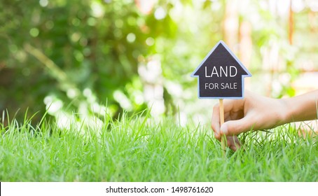 Residential construction project.  People are putting the house symbol with position pins and the words Land for sale and green grass in real estate sale or property investment concept,