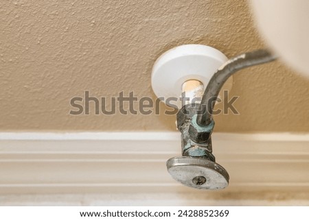 Residential home bathroom toilet water shut off valve. Replacing old leaking restroom wall supply line valve plumbing.