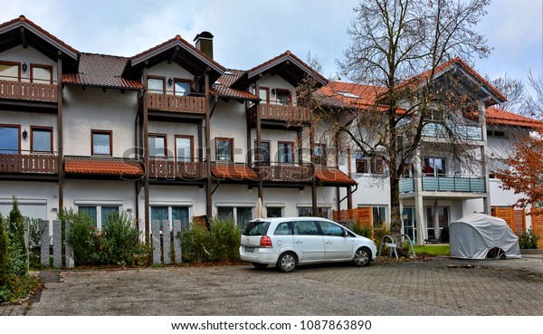 Residential house\
with balconies and red tile roof. Car in a parking lot. Urban\
landscape. German Architecture. Accommodation. West Europe.\
Germany, Zorneding - November 19, 2017\

