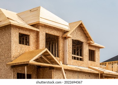 A residential house construction project showing plywood roof and dormer sheathing and oriented strand board or chip board sheathing on the exterior walls