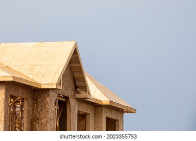 A residential house construction project showing plywood roof and dormer sheathing and oriented strand board (OSB) or chip board sheathing on the exterior walls - Shutterstock ID 2023355753