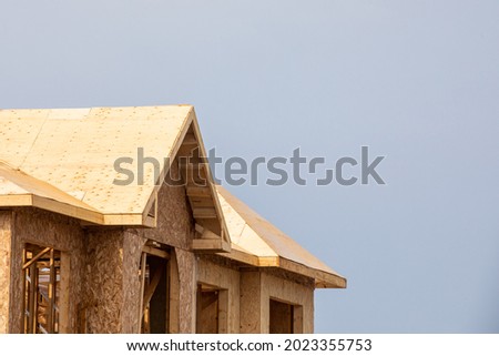 A residential house construction project showing plywood roof and dormer sheathing and oriented strand board (OSB) or chip board sheathing on the exterior walls