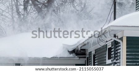 A residential house has snow blowing off its roof during a blizzard on Long Island New York in January 2022.