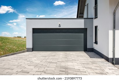 Residential house with modern garage with sectional door in front of landscape in summer