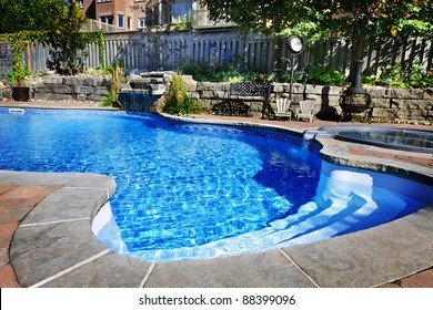 Residential inground swimming pool in backyard with waterfall and hot tub