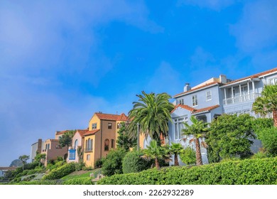 Residential landscape with colorful houses in San Francisco Califronia. Facade of homes in a beautiful neighborhood with vibrant foliage against blue sky.