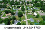 Residential neighborhood along Jefferson and Gentry Ave in Checotah, McIntosh County, Oklahoma, row of single-family houses with large backyard, grassy lawn, lush green tall mature trees, aerial. USA