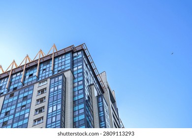 Residential skyscraper with reflective surfaces and angular blue glass design. Contemporary highrise with vertical blue glass panels and mirrored facades reaching into sky