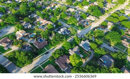Residential street in lush greenery neighborhood in Coppell Texas Dallas Fort Worth metroplex, row of detached single-family houses with swimming pools, large backyard, grassy lawn, aerial view. USA