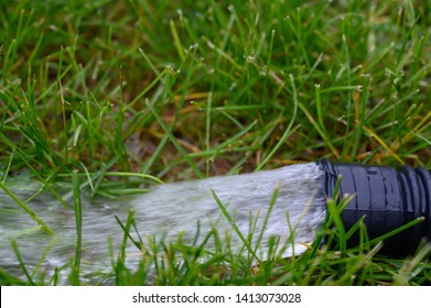 Residential Sump Pump Discharging Water From The End Of A Flexible Black Hose