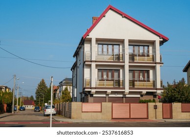 Residential three-story apartment building with brick and orange roof and large windows is located in a cozy bedroom community of the city. - Powered by Shutterstock