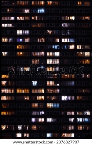 Residential tower apartment windows light up at night flat on