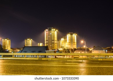 Residential Tower Blocks With A Starry Night Sky And Haze Around The Floodlights.