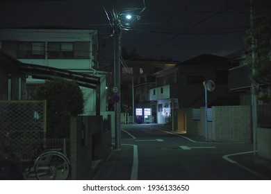 Residential urban area in the suburbs of Tokyo, view of an empty street illuminated by the green color of LED street lamp with drinks vending machines in the background - Powered by Shutterstock