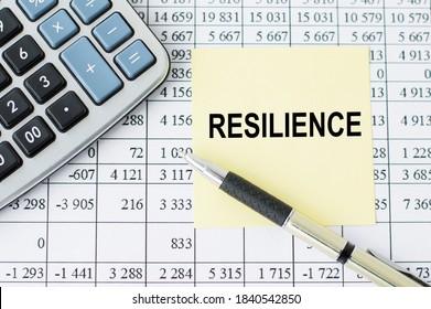 RESILIENCE Inscription On Yellow Note Paper On The Table, Near A Calculator, Pen And Financial Statements.