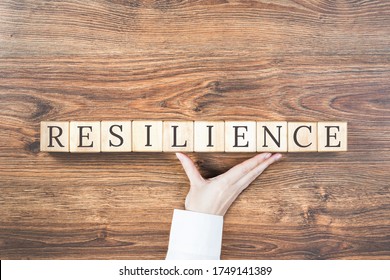 Resilience Word On Wooden Building Blocks With Supporting Hand. Recovering And Building Resilience Concept, Coping With Crisis. Copy Space