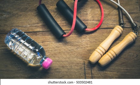 resistance band ,jump rope and water bottle on wooden block - vintage color style effect