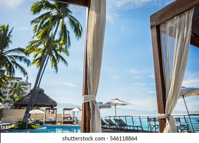 Resort Cabana Pool View With Palm Trees By Ocean Beach On Sunny Blue Sky Day