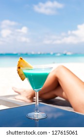Resort Vacation. Woman relaxing with Blue Curacao Cocktail. (Focus is on glass)