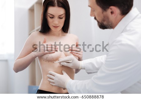 Respected plastic surgeon showing his patient the process of surgery