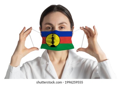 Respirator With Flag Of New Caledonia Doctor Puts On Medical Face Mask Isolated On White Background.