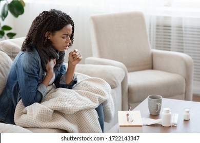 Respiratory illness. Sick black woman coughing hard at home, sitting alone on couch covered with blanket, side view with copy space - Shutterstock ID 1722143347
