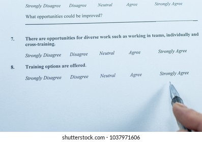 Respondent Holding A Pan In A Hand And Answeing Questions In Employee Survey. Questions Relating To Managerial Practices, Corporate Culture, Career Growth, And Professional Relationships. Close-up