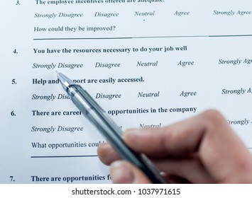 Respondent Holding A Pan In A Hand And Answeing Questions In Employee Survey. Questions Relating To Managerial Practices, Corporate Culture, Career Growth, And Professional Relationships. Close-up