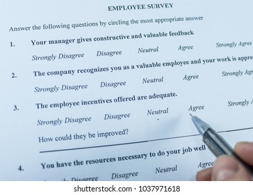 Respondent Holding A Pan In A Hand And Answeing Questions In Employee Survey. Questions Relating To Managerial Practices, Corporate Culture, Career Growth, And Professional Relationships. Close-up