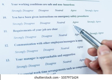 Respondent Holding A Pan In A Hand And Answeing Questions In Employee Survey. Questions Relating To Managerial Practices, Corporate Culture, Career Growth, And Professional Relationships. Close-up