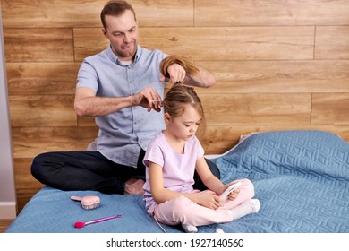 Responsible Father Dad Braiding Little Daughters Hair, Preparations For School, Handsome Male Caring Child Girl Sitting On Bed, Waiting. Everyday Life In Family