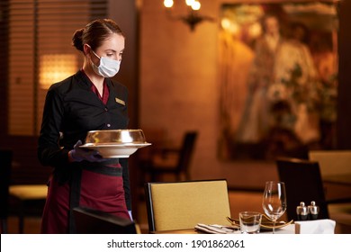Responsible woman in mask tables and serving food