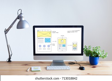 Responsive web design development technology concept with desktop computer in modern bright office and website wireframe sketch layout on screen, nobody