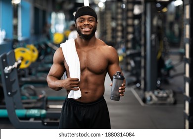 Rest After Workout. Happy African American Bodybuilder Holding Water Or Protein And Towel At Gym, Empty Space. Smiling Black Muscular Man Having Break While Exercising At Modern Gym