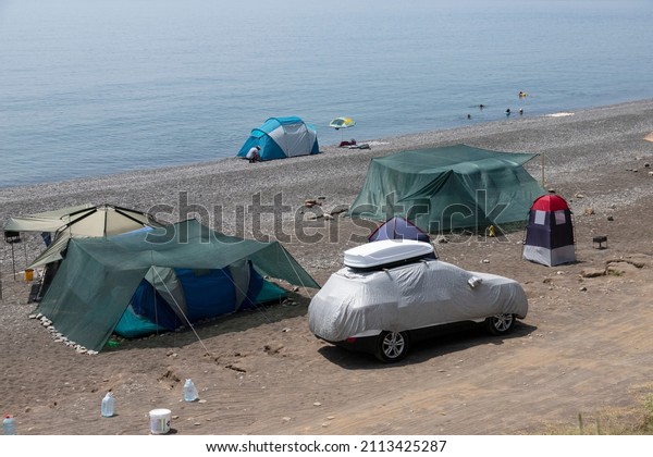 Rest by the sea with a\
camping car and a tourist tent. Car on the seashore. High quality\
photo