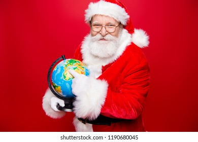 Rest relax carefree winter concept. Happiness aged stylish Saint Nicholas indicate show by finger on map globe offer spend December noel weekend in voyage trip isolated on shine red background