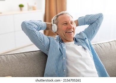 Rest And Relax Concept. Excited mature man sitting leaning back on couch listening to music, audio book or podcast, enjoying favorite playlist in wireless headphones holding hands behind head, closeup - Powered by Shutterstock