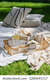 Rest In Summertime Outside, White Plaid With Cushions On Lawn In Yard, Bamboo Rattan Tray, Jug And Glassful With Lemon Water At Sunny Day